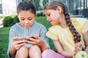 Foto von zwei Kindern, die auf ein Smartphone schauen